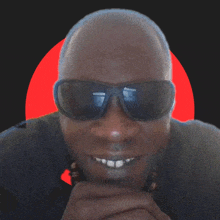 a man wearing sunglasses looks at the camera with his hand on his chin