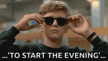 a young man wearing sunglasses is sitting in a library with the words `` to start the evening '' .