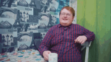 a man sits at a table with a cup of coffee in front of a wall that has paris on it