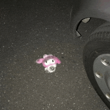 a stuffed animal laying on the ground next to a car