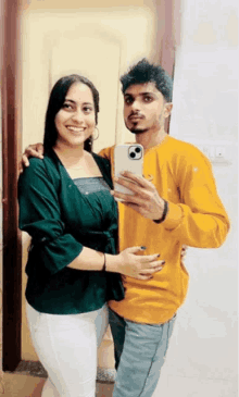 a man and a woman are posing for a picture in front of a mirror .