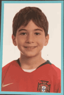 a young boy wearing a red nike shirt with the portuguese flag on it