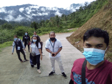 a group of people wearing face masks are standing on a concrete road