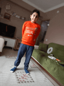 a young boy wearing an orange sweater that says casual