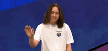 a young man wearing a white shirt that says nintendo on it waves his hand