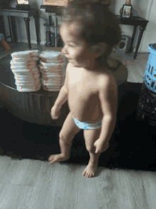 a toddler standing in front of a pile of diapers