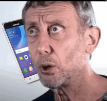 a man with a surprised look on his face is looking at a samsung phone