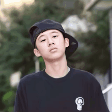 a young boy wearing a black hat and a black shirt with a white skull on it