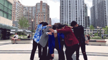 a group of people standing in a circle with their arms around each other in front of a city skyline