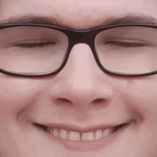 a close up of a person wearing glasses smiling