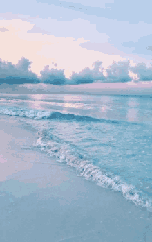 a beach with waves crashing against the sand and a cloudy sky