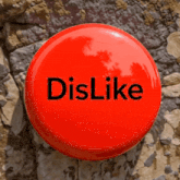 a red button that says dislike is sitting on a rocky surface