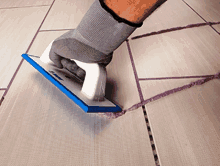 a person is grouting a tile floor with a tool that says ' scm ' on the side