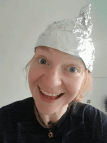 a woman wearing an aluminum foil hat smiles at the camera
