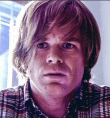 a close up of a man 's face with a plaid shirt