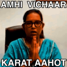 a woman is sitting in a chair with her hands folded in prayer .