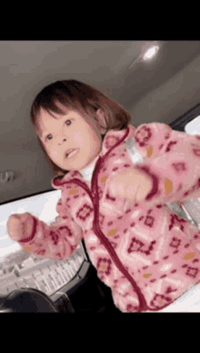 a little girl wearing a pink jacket with a floral pattern