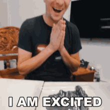 a man is sitting at a table with his hands folded and the words " i am excited " written below him