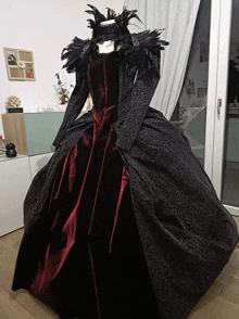 a mannequin wearing a black and red gown with feathers on it