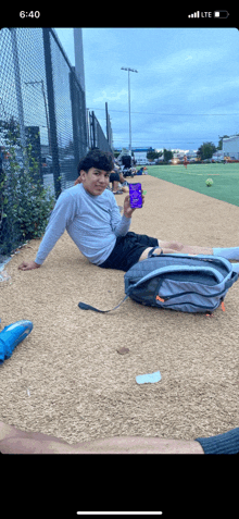 a man sits on the ground holding a purple container