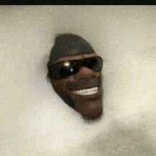 a man wearing sunglasses and a hat is taking a bath in a bathtub .