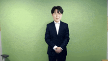 a man in a suit is standing in front of a green background