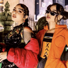 two women standing next to each other with one wearing an orange jacket that says xxx on it