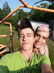 a man wearing a green shirt that says john taylor is taking a selfie with a woman wearing a flower headband