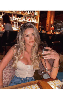 a woman holding a glass of wine in front of a bar