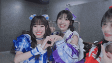 a girl in a blue and purple dress is making a heart shape with her hands