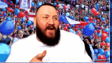 a man with a beard stands in front of a crowd of people with balloons and a banner that says wembley on it