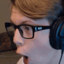 a man wearing glasses and headphones is looking at the camera with his mouth open .