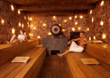 a man and a woman sit in a sauna with a gong in the background