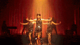 a group of women are dancing on a stage with red curtains behind them