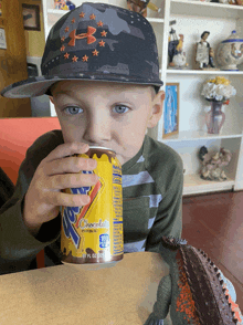 a young boy wearing a hat drinks from a can that says ' chocolate ' on it