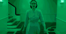 a woman in a nurse 's uniform is walking down a hallway with green lights behind her