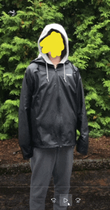 a man wearing a black jacket with a white hood is standing in front of trees