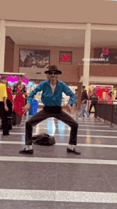 a man in a blue shirt and hat is dancing in front of a h & m sign
