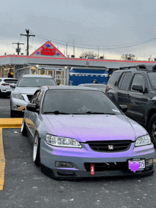 a purple honda car is parked in a parking lot in front of a car wash