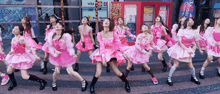 a group of young girls in pink dresses are dancing in front of a longines store
