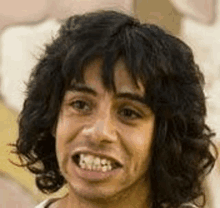 a close up of a man 's face with long curly hair and a funny face .