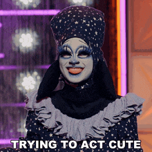 a drag queen is smiling with the words trying to act cute above her