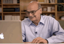 an older man wearing glasses is using an apple laptop computer