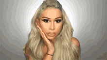 a woman with long blonde hair is touching her face while looking at the camera .