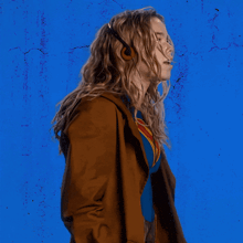 a woman in a superman costume stands in front of a blue wall