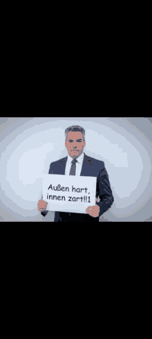 a man in a suit and tie is holding a sign that says " außen hart innen zartli "