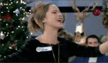 a woman with a name tag that says ' eliza ' on it is dancing in front of a christmas tree