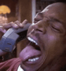 a man is sticking his tongue out while talking on a phone .