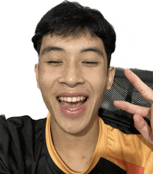 a man wearing a black and orange shirt is giving a peace sign