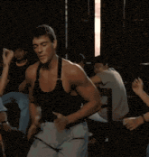 a man in a black tank top is dancing in a room